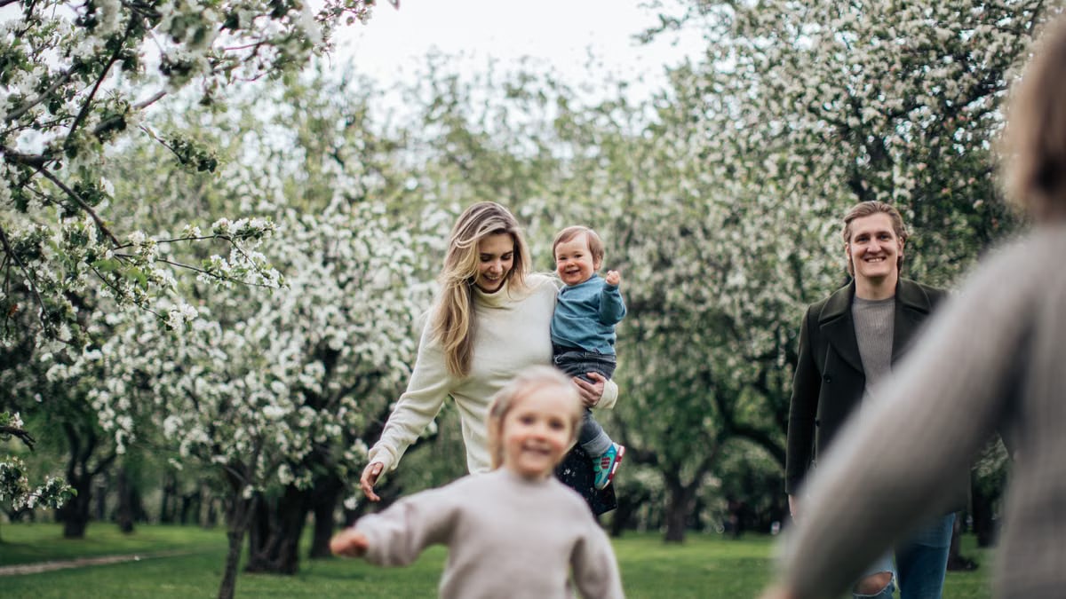A joyful family enjoys a playful day outdoors amidst blossoming trees in spring.